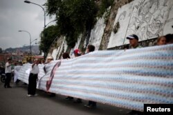 Demonstrators hold a banner made from three thousand two-bolivar-bills, that is equivalent approximately to $1 according to the black market exchange rate, in Caracas, Venezuela, June 10, 2017.