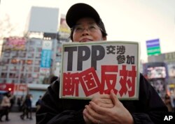 FILE - A protester holds a sign reading "We oppose Japan to join the TPP negotiation talks" during a rally against the Trans-Pacific Partnership in Tokyo.