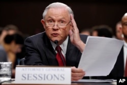FILE - Attorney General Jeff Sessions reads from a statute about his recusal from the Russia probe while testifying on Capitol Hill in Washington, June 13, 2017, before a Senate Intelligence Committee hearing.