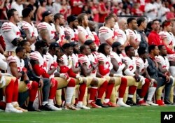 FILE - Members of the San Francisco 49ers kneel during the national anthem as others stand during the first half of an NFL football game against the Arizona Cardinals, Oct. 1, 2017, in Glendale, Arizona.