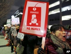 Protesters hold placards during an anti-nuclear rally near the Prime Minister's office in Tokyo, March 11, 2016.