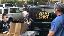 In this photo provided by Oregon Health & Science University, registered nurse Karl Tutsch, right, receives meals on behalf of Michael Menner, left, and Tara Caruy, of Amalfi's, during a delivery of hot pasta meals to Oregon Health & Science University in Portland, Ore., Thursday, Dec. 31, 2020. The program that provided the meals, funded by a grant from an Oregon-based insurance fund, recently expired but the hospital is hoping for new donations to reboot it as COVID-19 variants could cause a new surge of cases. (Oregon Health & Science University via AP)