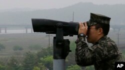 Военнослужащий морской пехоты Южной Кореи смотрит в бинокль в сторону Севера , Южная Корея, 16 мая 2018 года.