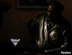 FILE - A Daiquiri is seen on the counter beside a life-size bronze statue of United States writer Ernest Hemingway at his regular spot at The Floridita bar in Havana, July 1, 2010.