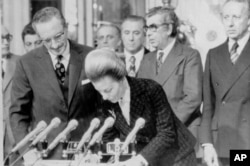 FILE - Then-Argentine President Isabel Peron signs government records after swearing in five new cabinet ministers in Buenos Aires, Argentina Aug. 11, 1975.