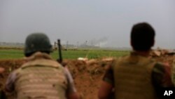 FILE - Smoke rises from positions in the IS-held town of Besher, during a military operation to regain control of the small town, outside the oil-rich city of Kirkuk, 180 miles (290 kilometers) north of Baghdad, Iraq, April 10, 2016.
