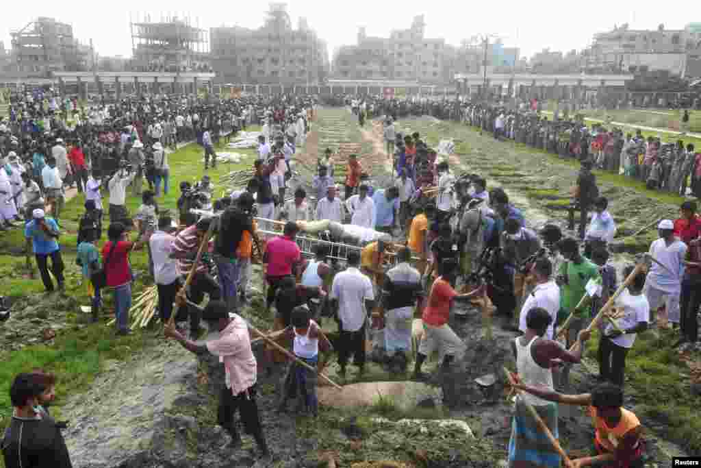 Workers dig mass graves during a burial of unidentified garment workers, who died in the collapse of the Rana Plaza building in Savar, Bangladesh, May 1, 2013.