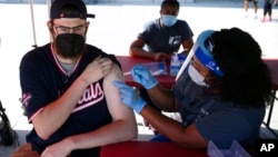 Chandler Millard, left, of Alexandria, Va., receives a Johnson & Johnson vaccine at a COVID-19 vaccination clinic hosted by the Washington Nationals outside of Nationals Park before a baseball game against the Colorado Rockies, Sept. 18, 2021. (AP Photo/Nick Wass)