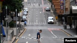 Seorang pria melintasi jalan pusat kota yang sebagian besar kosong ketika orang-orang di Greater Brisbane telah diperintahkan untuk dikunci ketika pihak berwenang mencoba untuk menekan klaster COVID-19 yang berkembang di Brisbane, Australia, 30 Maret 2021. (Foto: Reuters)