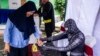 Indonesian election workers dressed in superhero costumes register voters at a polling station in Surabaya, April 17, 2019.