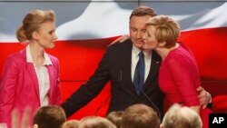 Andrzej Duda, candidate of the conservative opposition Law and Justice party, receives a kiss from his wife Agata, right, as his daughter Kinga, left, watches, after the announcement of the first exit polls in the first round of the Polish presidential elections in Warsaw, Poland, Sunday, May 10, 2015.
