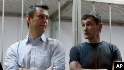 FILE - Russian opposition activist and anti-corruption crusader Alexei Navalny, 38, left, and his brother Oleg Navalny, 31, stand at a court in Moscow, Russia, Dec. 30, 2014. 