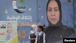 Girls walk past campaign posters of candidates ahead of parliamentary elections, in Tikrit, Iraq, April 29, 2018.