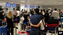 In this April 17, 2021, file photo, people check in for a flight to Miami at Silvio Pettirossi Airport, in Luque, Paraguay. 