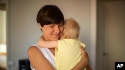 In this photo taken on Wednesday, June 19, 2019, Clara Massons holds her two years old son Jaume at her home in Barcelona, Spain. (AP Photo/Emilio Morenatti)