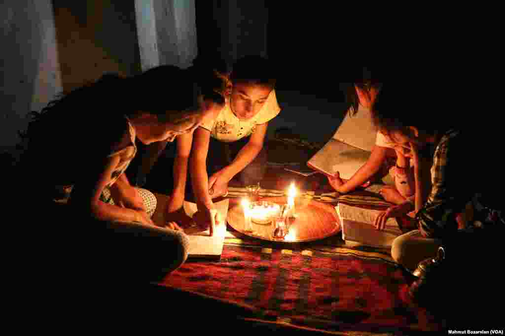 The government has cut power and water to Sur, in Diyarbakir, Turkey, as efforts are made to rebuild it. A family reads by the light of candles inside their home.