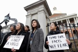 Members of Massachusetts' Asian American Commission,stand together during a March 12, 2020, protest condemning what they say is racism, fear-mongering and misinformation aimed at Asian communities amid the widening coronavirus pandemic.