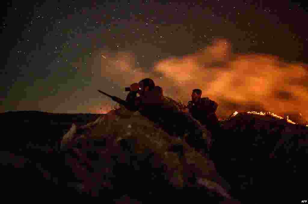 A fighter with the Syrian Democratic Forces (SDF) uses a binocular in a position in the eastern Syrian province of Deir Ezzor outside the Islamic State group's embattled holdout of Baghouz, on March 11, 2019.