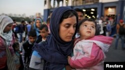 FILE - Syrian refugees disembark from a Greek ferry after arriving in the port of Piraeus near Athens, June 14, 2015.