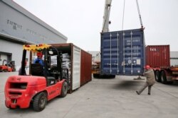 FILE - Men work on unloading the rubber imported from Belt and Road Initiative (BRI) countries at a bonded logistics center in Nantong, Jiangsu province, China, May 17, 2019.