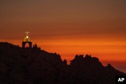 A cross sits on a cliff overlooking the sunset over the scenic Kadisha Valley, a holy site for Lebanon's Maronite Christians, in Bcharre, Lebanon, on July 21, 2023.