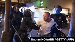 Polisi Portland menahan seorang pria yang bersama saat dia bereaksi beberapa menit setelah insiden penembakan pada 29 Agustus 2020 di Portland, Oregon. (Foto: AFP/Nathan Howard / Getty)