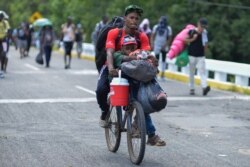 Two migrants bike down Highway 200 en route to Huixtla with all their belongings near Tapachula, Chiapas state, Mexico, Oct. 12, 2019.