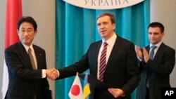 FILE - Japanese Foreign Minister Fumio Kishida, left, and Minister of Economical Development and Trade of Ukraine Pavlo Sheremeta, center, exchange signed documents while meeting in Kyiv,Ukraine, July 17, 2014. 