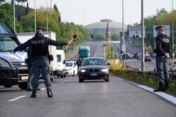 Police officers pull over cars at a road block on a main road leading out of the city, in Rome, April 13, 2020.