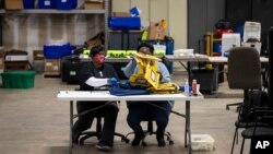 Elections workers at the Fulton County Georgia elections warehouse check in voting machine memory cards that store ballots following the Senate runoff election in Atlanta, Jan. 5, 2021.