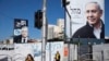 Para pejalan kaki melewati poster kampanye Partai Likud yang dipimpin Perdana Menteri Israel Benjamin Netanyahu (kanan) dan Partai Biru dan Putih, pimpinan Benny Gantz (kiri) di Bnei Brak, Israel, 1 Maret 2020. (Foto: AP)