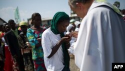 Un prêtre distribue l’eucharistie au cours d’une messe dans un camp des personnes déplacées à la périphérie de Goma, Nord-Kivu, 25 novembre 2012.