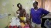 A victim of latest bomb explosion at a bus park gets a visit from his brother at the Asokoro hospital in Abuja, Nigeria, April 16, 2014.