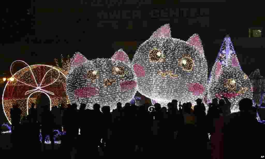 People are silhouetted against illuminations for the Christmas and New Year holiday season at Ilsan Lake Park in Goyang, South Korea, Dec. 25, 2016.