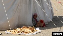 A girl sits outside a tent at al-Wara camp for internally displaced people in al-Khukha of Hodeidah province, Yemen, Nov. 21, 2021.