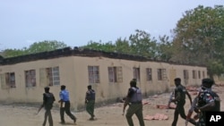 Photo d’archives : Les forces de sécurité devant une école secondaire publique incendiée dans la ville de Chibok, Nigeria – 21 avril, 2014.