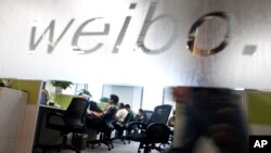 FILE - Employees work at their desks at a Sina Weibo office in Beijing. 