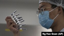 In this Sept. 24, 2020, file photo, an employee manually inspects syringes of the SARS CoV-2 Vaccine for COVID-19 produced by Sinovac at its factory in Beijing. (AP Photo/Ng Han Guan, File)
