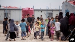 FILE - Women and children gather in front their tents at al-Hol camp, which houses 60,000 refugees, including families and supporters of the Islamic State group, many of them foreign nationals, in Hasakeh province, Syria, May 1, 2021.