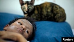 In this file photo, Samruei, a terminally ill Thai woman rests with her cat at a hospice for those dying of AIDS at a Buddhist temple Wat Prabat Nampu in Lop Buri.