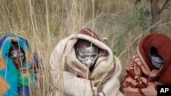 Xhosa boys covered with a blankets and smeared with chalky mud sit in a field as others undergo a traditional male circumcision ceremony into manhood near the home of former South African president Nelson Mandela in Qunu, South Africa, June 30, 2013.
