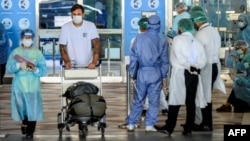 Seorang karyawan yang mengenakan alat pelindung diri (APD) mengantar penumpang penerbangan internasional yang tiba di Bandara Suvarnabhumi, Bangkok, ke mobil transfer hotelnya untuk Karantina Negara Alternatif (ASQ) wajib 14 hari, 16 November 2020. 