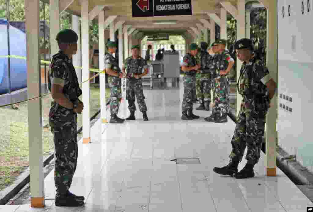 Indonesian soldiers stand guard in a hallway at the police hospital where the bodies of the victims of AirAsia Flight 8501 are brought into for identification process, in Surabaya, East Java, Indonesia, Dec. 31, 2014. 
