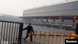 一名保安人员星期天1月26日正在北京四惠长途车站关上铁门。