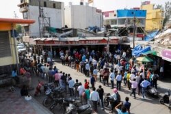 People queue outside a wine store to buy liquor after the Delhi government ordered a six-day lockdown to limit the spread of the coronavirus disease, in New Delhi, India, April 19, 2021.
