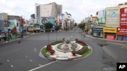 People ride on a motorcycle through a quiet intersection in Ho Chi Minh City, Vietnam, Monday, Aug. 23, 2021. (Bui Van Lanh/VNA via AP)