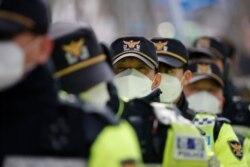Police officers wearing face masks stand guard during a rally in downtown Seoul, South Korea, Feb. 22, 2020. South Korea on Saturday reported a six-fold jump in viral infections in four days to 433.