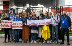 Journalists of Belarusian TUT.BY media outlet hold banners reading "I'm not protesting; I'm working", "This is me at work", "Freedom for journalists!", from left to right, as they stand in front of a police station in Minsk, Belarus, Sept. 2, 2020.