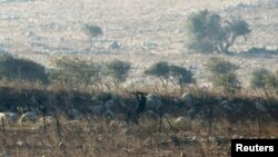 Seorang pemberontak menembak dalam pertarungan dengan tentara Suriah di dekat Dataran Tinggi Golan (1/9). (Reuters/Baz Ratner)