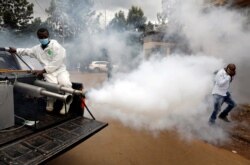 A man walks through smoke generated by Nairobi municipality worker in an effort to fight against the spread of the coronavirus disease (COVID-19) in the Kawangware neighborhood of Nairobi, Kenya, May 2, 2020.